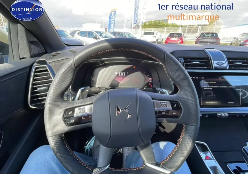 Vue intérieure centrée sur le volant cuir noir avec surpiqûres marron du DS7 bleu, tableau de bord et écran tactile visibles.