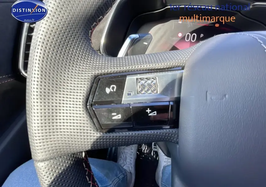 Gros plan sur le volant cuir perforé du DS7 1.5 BlueHDi 130, avec commandes multifonctions et coutures rouges visibles.
