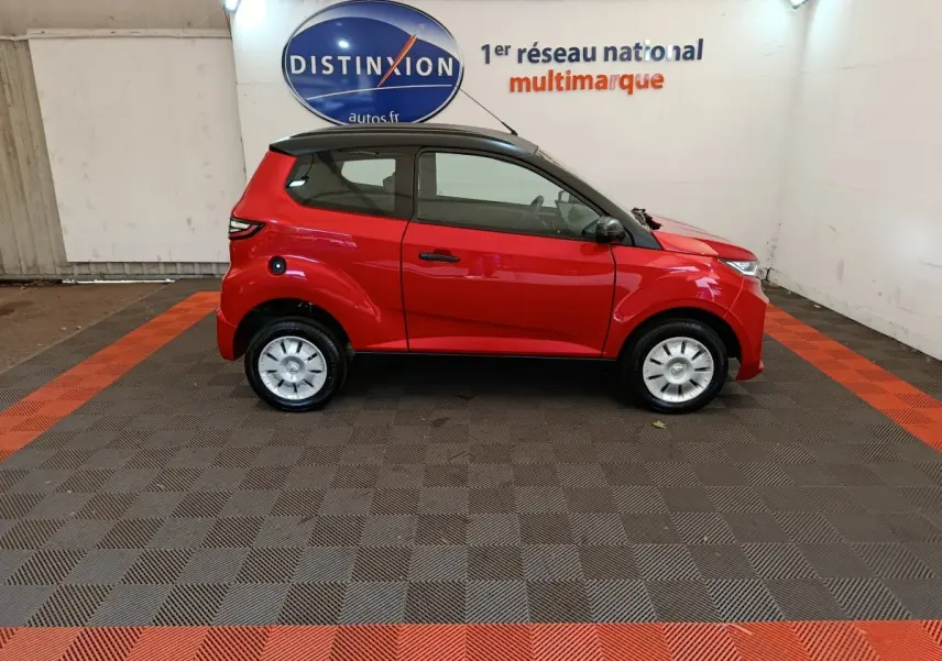 Vue de profil côté gauche d'une Aixam Ambition 0.5 City Crossline Pack rouge 2024 avec toit noir en intérieur showroom.