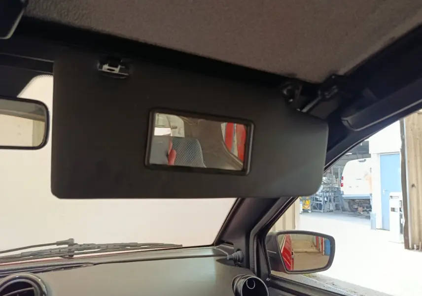 Vue intérieure côté conducteur de l'AIXAM Ambition 0.5 City Crossline Pack 2024 rouge, avec pare-soleil et rétroviseur extérieur visible.