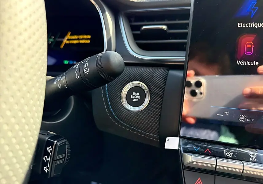 Détail intérieur côté gauche du tableau de bord gris avec bouton Start Engine Stop et écran tactile multifonction.