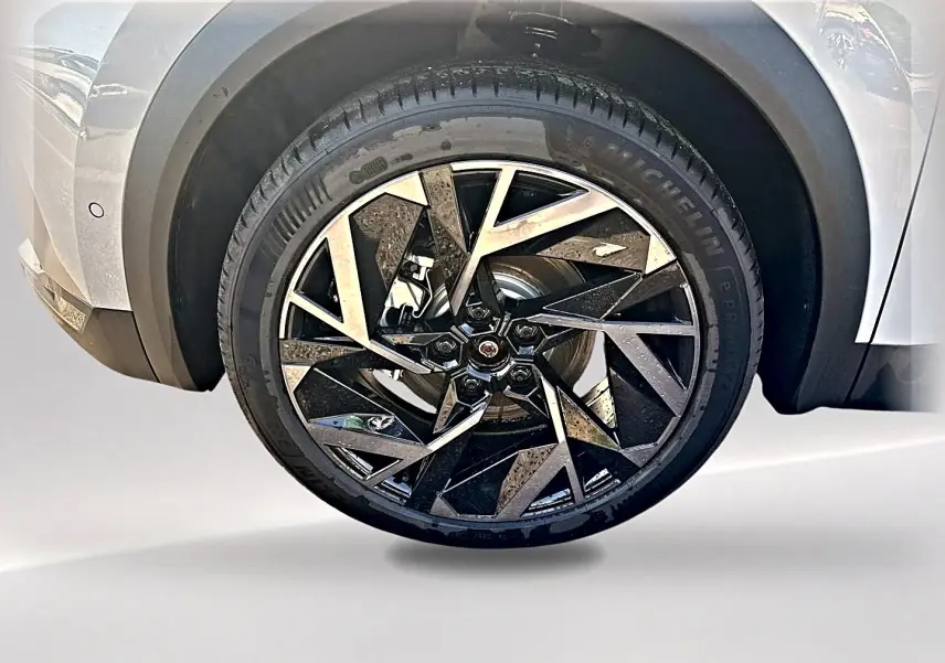 Gros plan sur la roue avant gauche gris rafale du Renault Symbioz 1.8 e-tech avec jante alu noire et argentée au design géométrique.