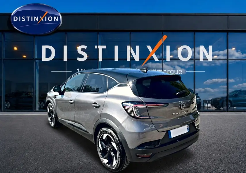 Vue 3/4 arrière droite d'un Renault Captur gris cassiopée avec jantes noires et vitres surteintées devant un bâtiment Distinxion.
