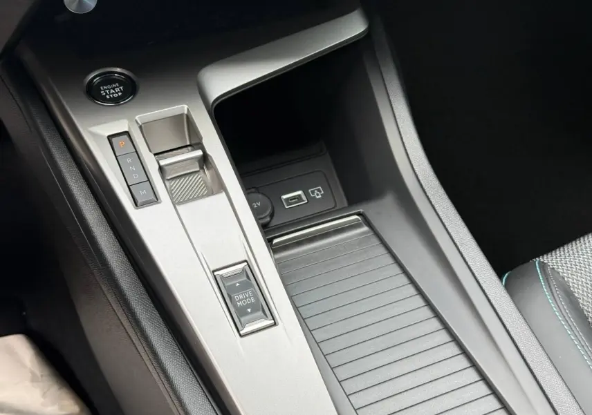 Gros plan sur la console centrale argentée avec sélecteur de boîte auto et bouton Drive Mode dans une Peugeot 308 SW rouge.