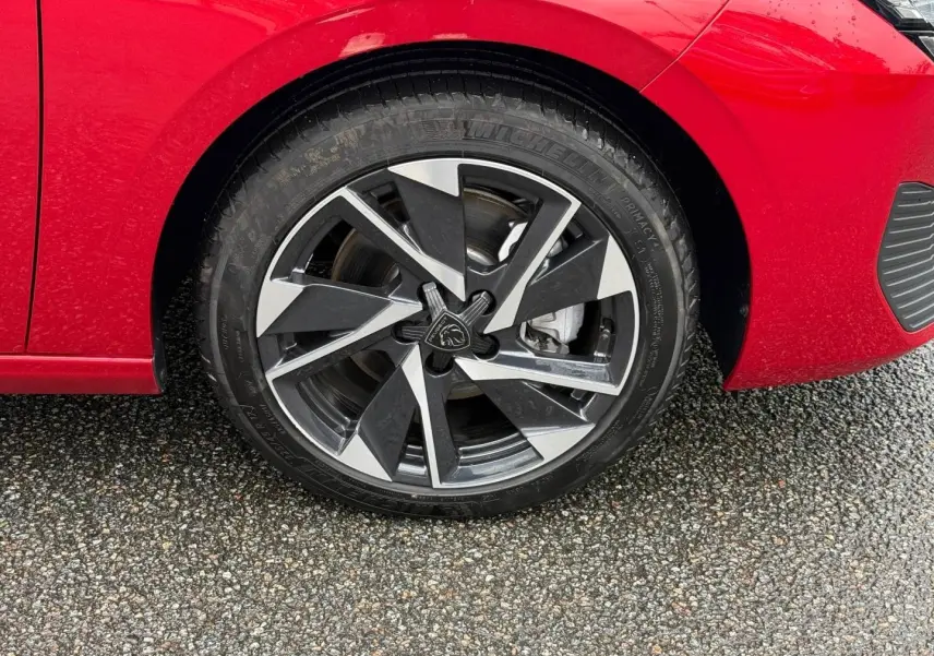 Gros plan sur la roue avant gauche avec jante alu noire et argentée du Peugeot 308 SW rouge Elixir.