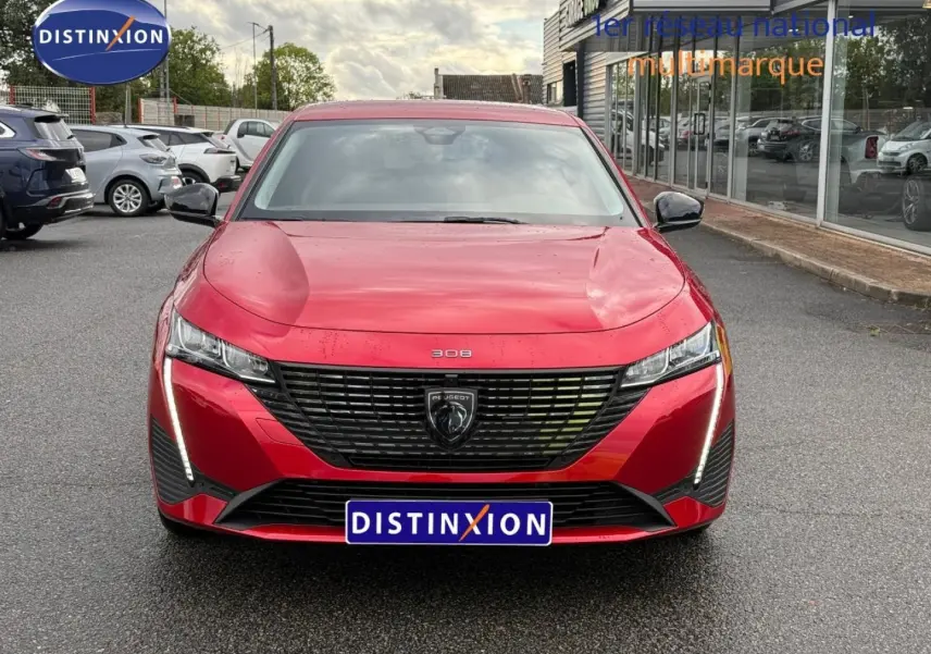 Vue avant frontale d'une Peugeot 308 SW rouge Elixir avec calandre noire et feux LED verticaux allumés.