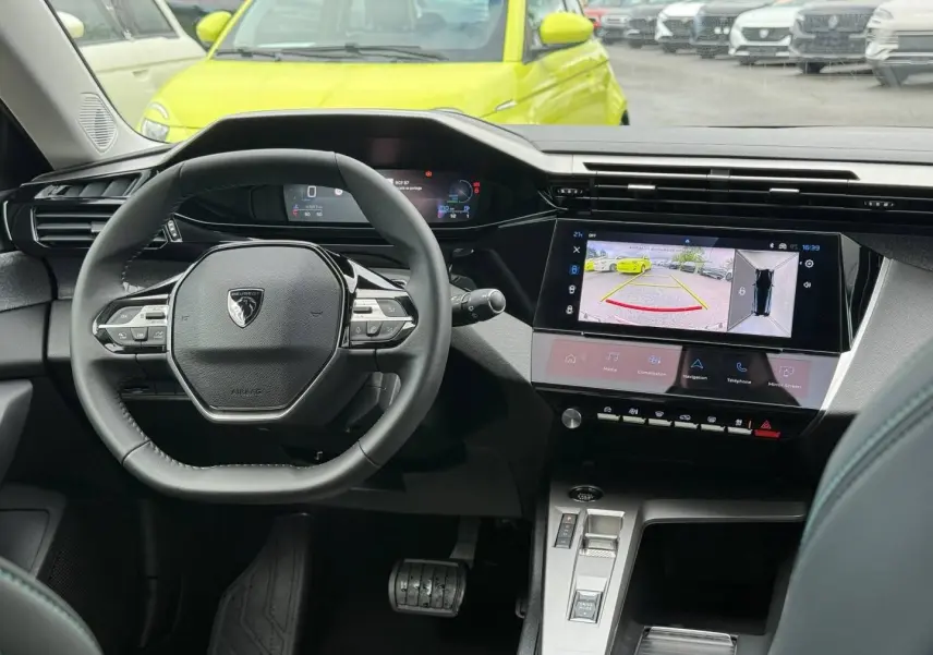 Vue intérieure centrée sur le volant et l’écran tactile du tableau de bord d’une Peugeot 308 SW rouge Elixir.