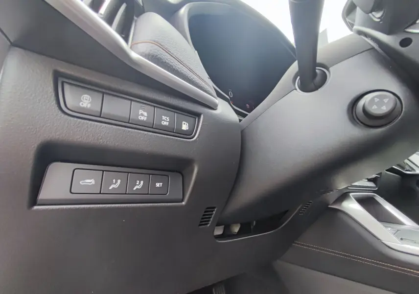 Détail des commandes côté gauche du tableau de bord du Mazda CX-60 blanc métal 2024 avec boutons de réglages et sécurité.