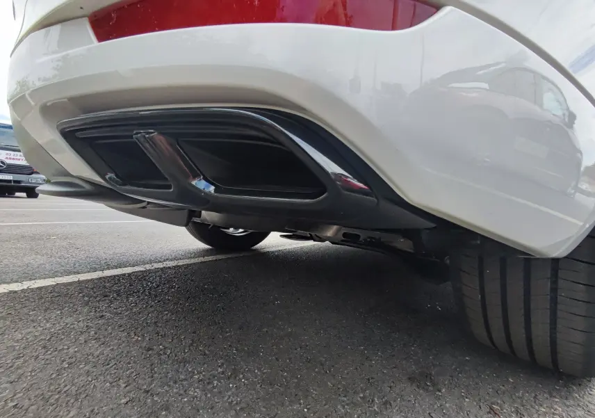 Gros plan sur le diffuseur arrière noir et la roue droite d'un Mazda CX-60 blanc métal 2024 hybride rechargeable.