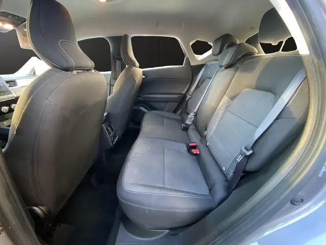 Vue intérieure arrière droite du Renault Captur TCE 90 Equilibre 2023 gris Cassiopée, sièges tissu gris foncé avec ceintures de sécurité.