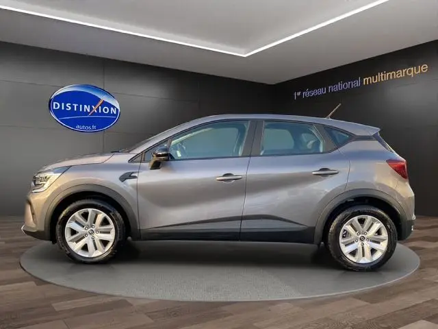 Profil côté gauche d'un Renault Captur TCE 90 Équilibre gris Cassiopée 2023 sur plateau en showroom.