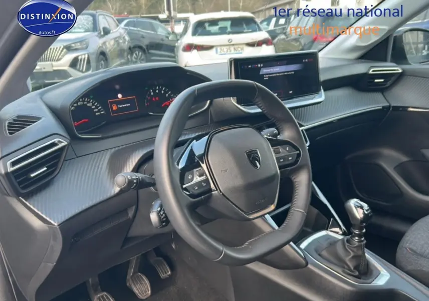 Intérieur de la Peugeot 208 1.2 100 Style 2025, vue du poste de conduite avec volant cuir et boîte manuelle.
