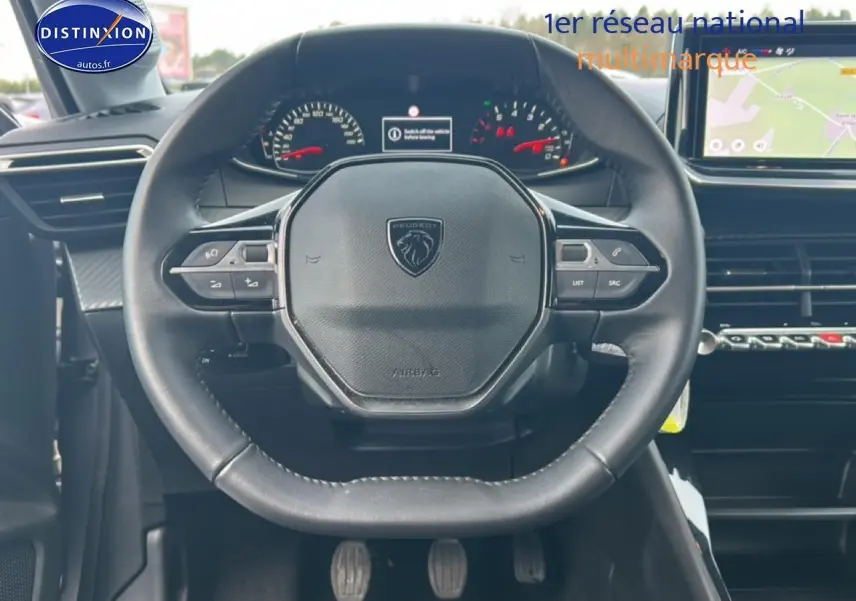 Vue intérieure centrée sur le volant Peugeot 208 1.2 100 style avec commandes intégrées et tableau de bord numérique.