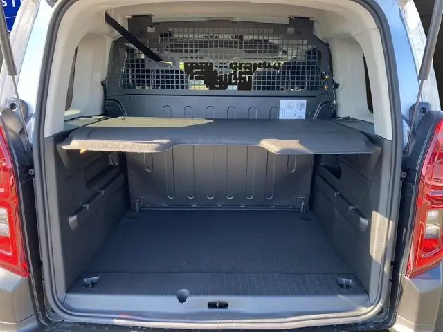Vue arrière du coffre ouvert du Citroën Berlingo N1 BlueHDi 130 gris Artense, avec cloison métallique et tablette de rangement.