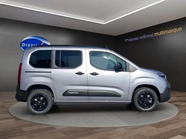 Vue de profil droit du Citroën Berlingo gris Artense avec jantes noires et vitres teintées en showroom.