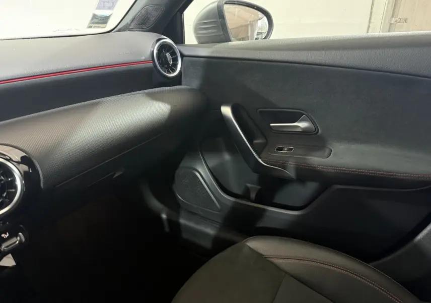 Vue intérieure côté passager de la Mercedes Classe A 200 AMG Line 2021, avec garnitures noires et surpiqûres rouges.