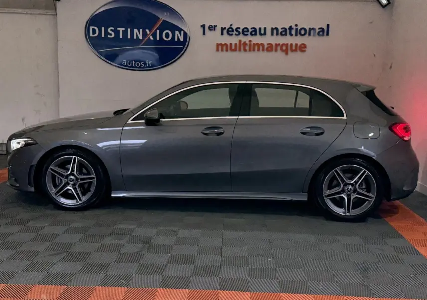 Vue de profil côté gauche d'une Mercedes Classe A 200 AMG Line gris foncé en intérieur sur sol damier.