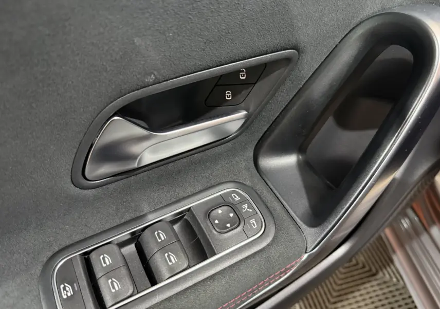 Gros plan sur la porte côté conducteur de la Mercedes Classe A 200 AMG Line 2021, garniture noire avec surpiqûres rouges.