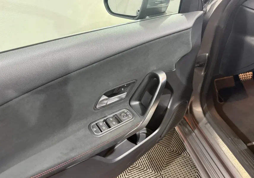 Détail de la porte avant gauche gris foncé de la Mercedes Classe A 200 AMG Line avec commandes des vitres et poignée alu.