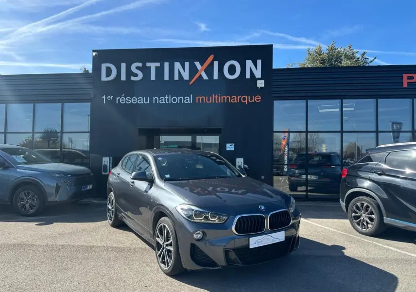 BMW X2 gris foncé vue 3/4 avant droit, avec jantes alliage 19 pouces et calandre double haricot distinctive.