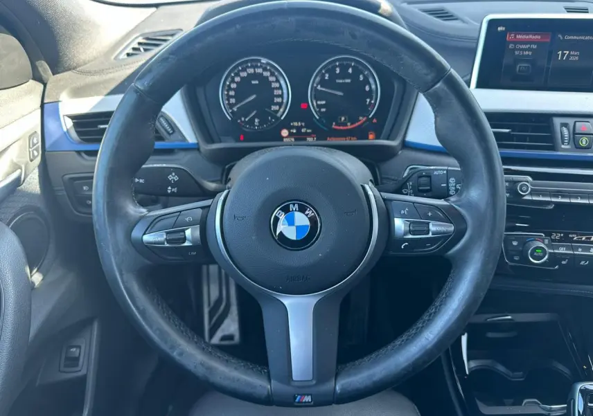 Vue intérieure centrée sur le volant M cuir noir de la BMW X2 2020 avec tableau de bord et écran multimédia visible.