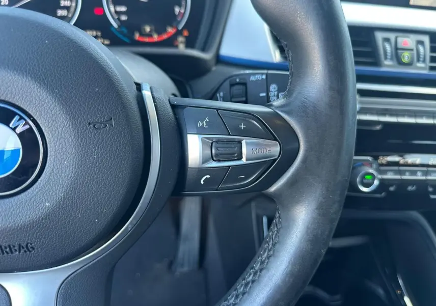 Gros plan sur le volant cuir M de la BMW X2 2020 avec commandes multifonctions et tableau de bord partiel en arrière-plan.