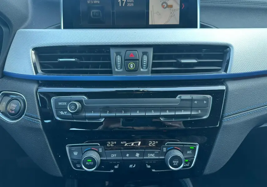 Vue centrée sur la console centrale intérieure du BMW X2 gris foncé, avec commandes climatisation et écran multimédia.