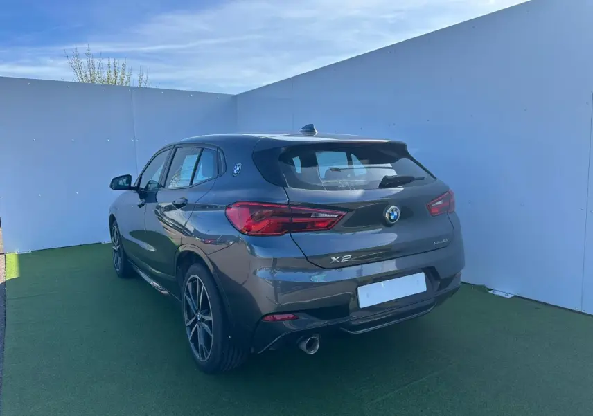 BMW X2 gris foncé vue 3/4 arrière droit, avec jantes alliage 19 pouces et logo BMW sur custode.