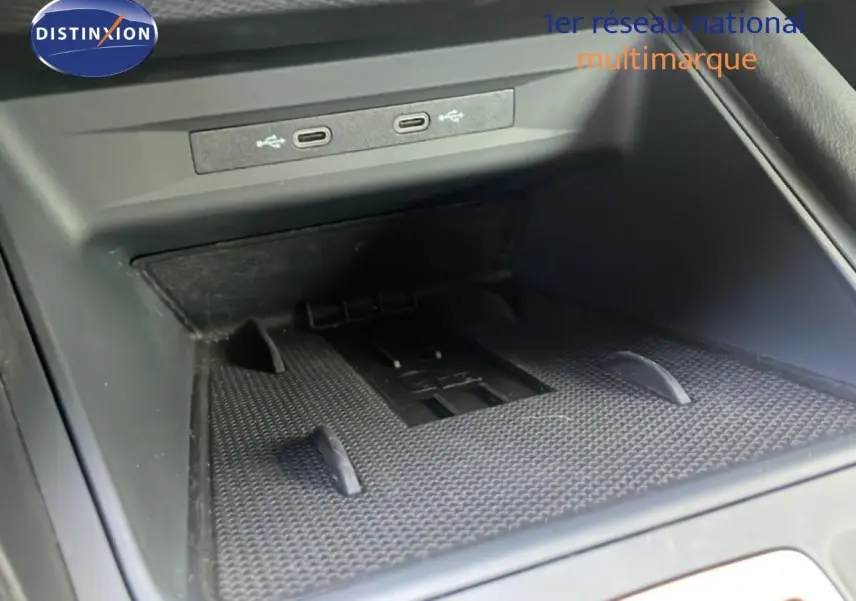 Gros plan sur la console centrale du CUPRA Formentor blanc neige métal, montrant les ports USB et un espace de rangement.