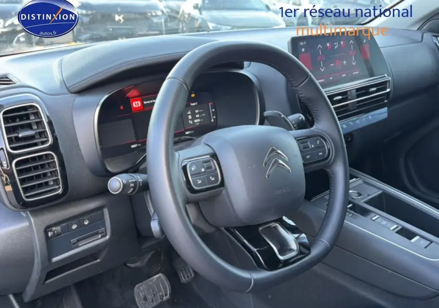 Vue intérieure du poste de conduite du Citroën C5 Aircross 2025, volant multifonction et écran tactile visibles.