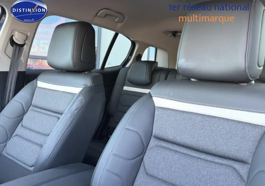 Vue intérieure des sièges avant et arrière du Citroën C5 Aircross 2025, avec sellerie gris clair et détails en cuir noir.