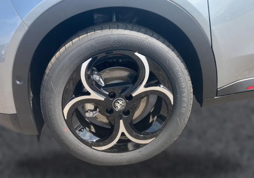 Gros plan sur la roue avant droite gris/noir d'une Alfa Romeo Junior 1.2 hybride 2026 avec jante alliage noire et argentée.