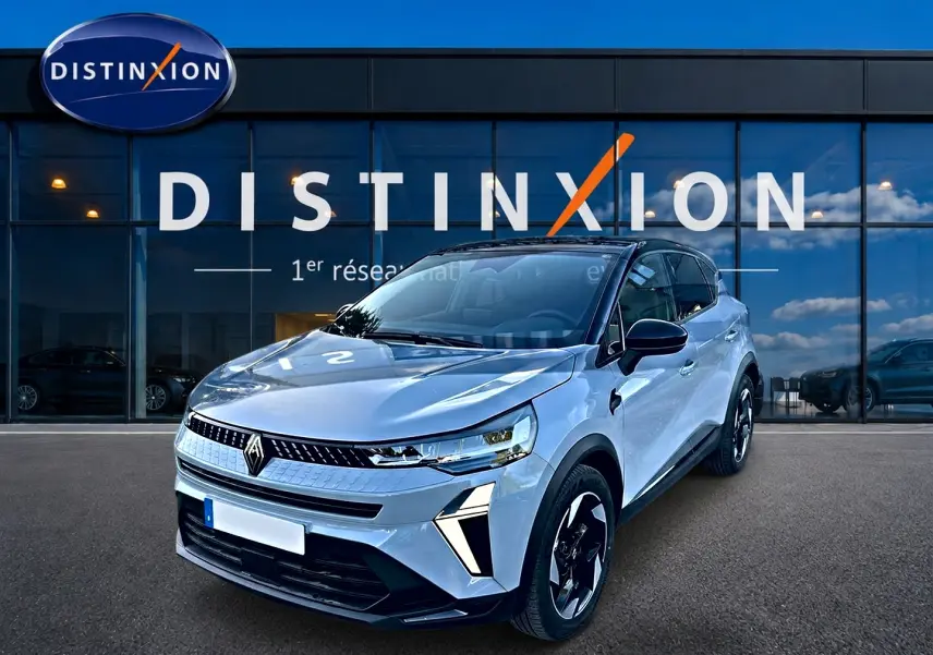 Vue 3/4 avant du Renault Captur gris rafale, avec jantes noires et toit noir contrastant, devant une vitrine Distinxion.