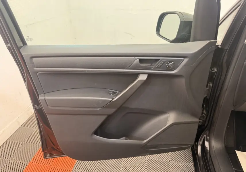 Vue intérieure de la porte avant gauche noire du Volkswagen Caddy 2019, avec commandes des vitres et rétroviseur.