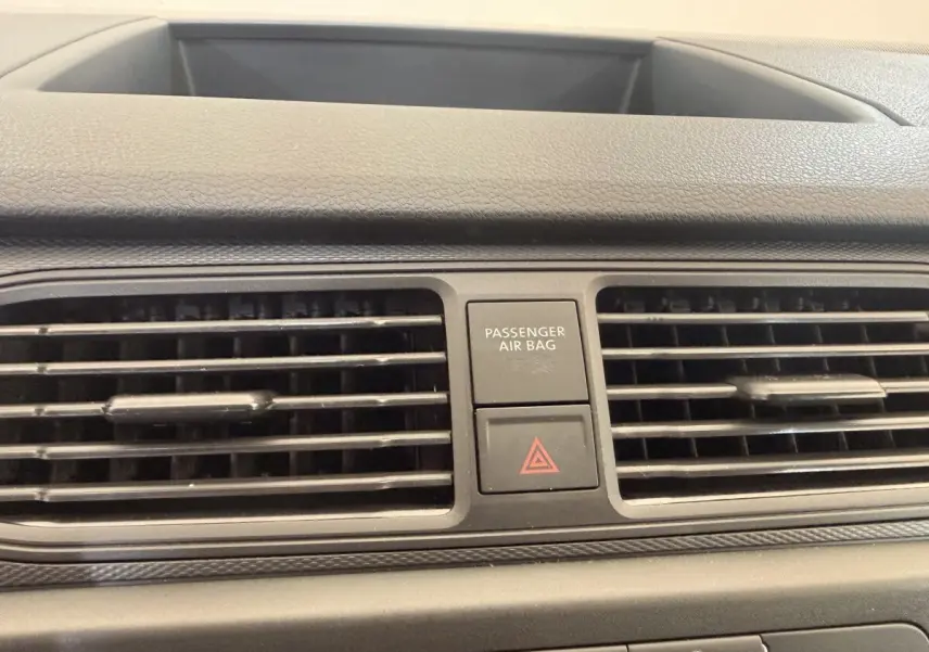 Gros plan sur la grille d’aération centrale et les boutons de sécurité du tableau de bord du Volkswagen Caddy noir.
