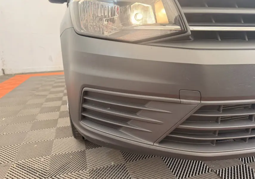 Gros plan sur l'avant gauche noir du Volkswagen Caddy 2.0 TDI 2019 avec phare allumé et calandre visible.
