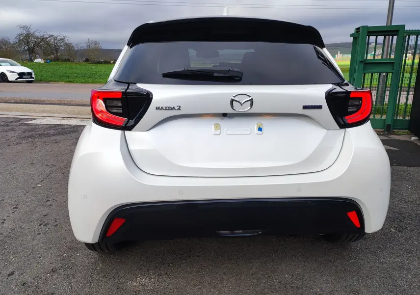 Vue arrière d'une Mazda2 hybride blanc métallisé avec feux arrière LED et logo Mazda bien visibles.