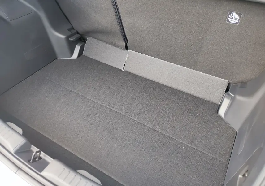 Coffre spacieux vu de dessus dans une Mazda2 Hybrid 2024 blanc métallisé, avec revêtement tissu gris foncé et fixations ISOFIX.