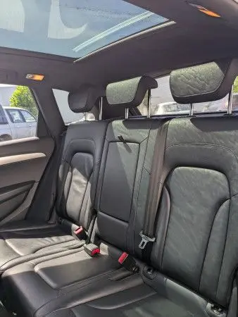 Vue intérieure arrière montrant les sièges en cuir noir et le toit ouvrant panoramique d'un Audi Q5 2012.