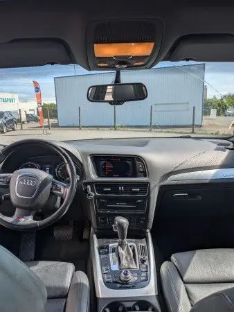 Vue intérieure avant de l'Audi Q5 noir 2012, montrant le tableau de bord, volant, console centrale et levier de vitesse automatique.