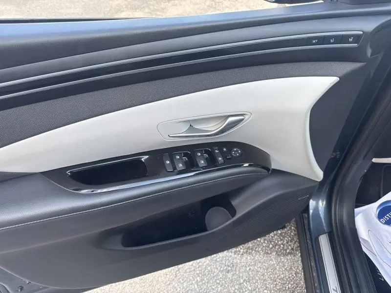 Vue rapprochée de la porte avant gauche du Hyundai Tucson 2021 en Teal Blue Métal avec commandes électriques et insert clair.