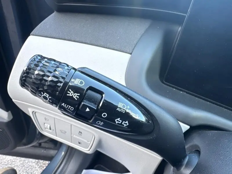 Gros plan sur la commande de phares noire à effet diamantée dans l'habitacle clair du Hyundai Tucson 2021.