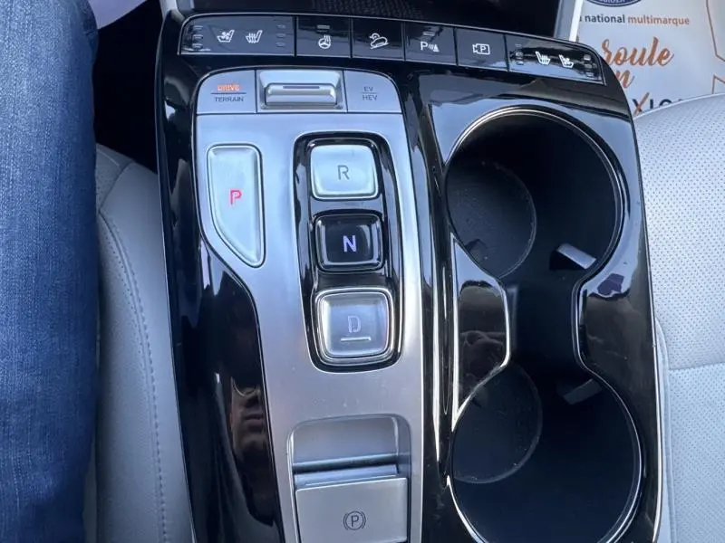 Gros plan sur la console centrale noire du Hyundai Tucson 2021 avec boutons de boîte auto et porte-gobelets.
