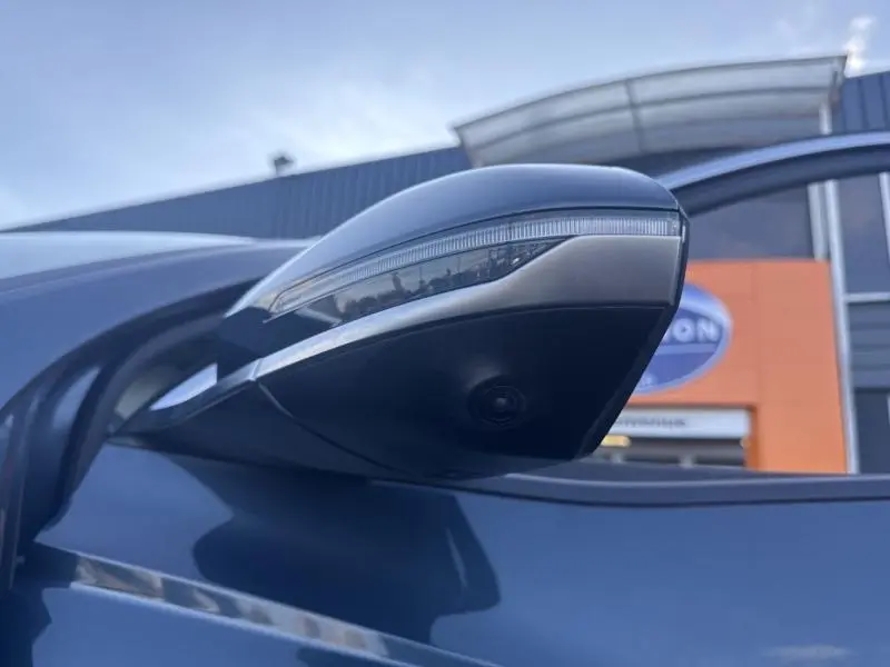 Gros plan sur le rétroviseur côté gauche bleu Teal Blue Métal du Hyundai Tucson 2021 avec caméra intégrée.