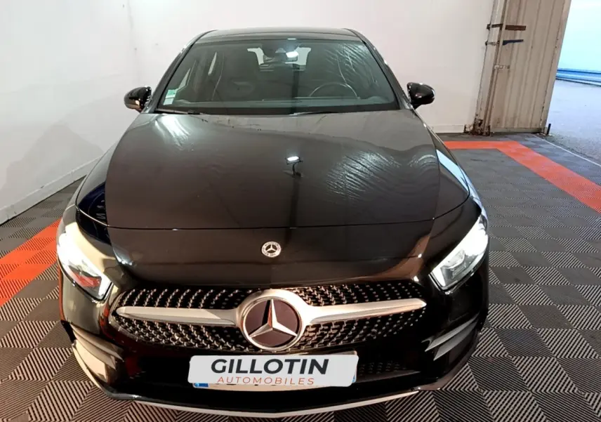 Vue avant d'une Mercedes Classe A 200 AMG Line noire avec calandre distinctive et phares LED allumés.