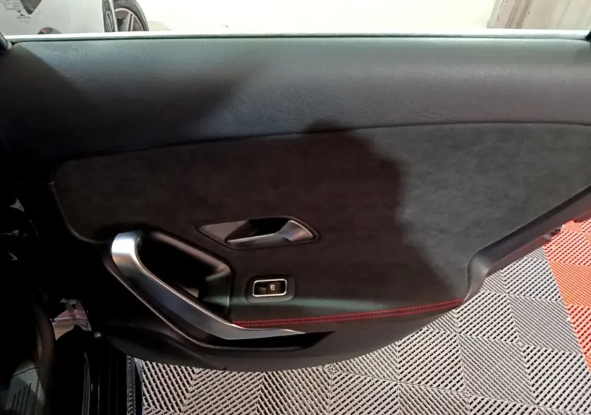 Gros plan sur la porte intérieure côté gauche noire avec surpiqûres rouges et poignée alu de la Mercedes Classe A AMG Line.