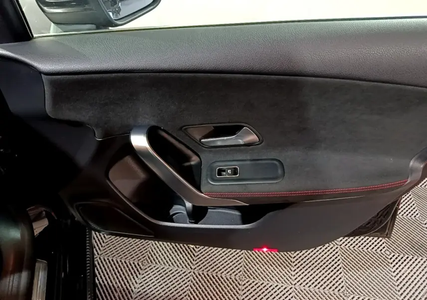 Vue intérieure du panneau de porte côté conducteur d'une Mercedes Classe A 200 AMG Line noir avec surpiqûres rouges.