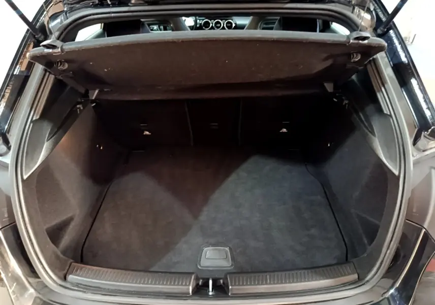 Coffre ouvert vu de l'arrière d'une Mercedes Classe A 200 AMG Line noire, montrant l'espace de chargement vide.