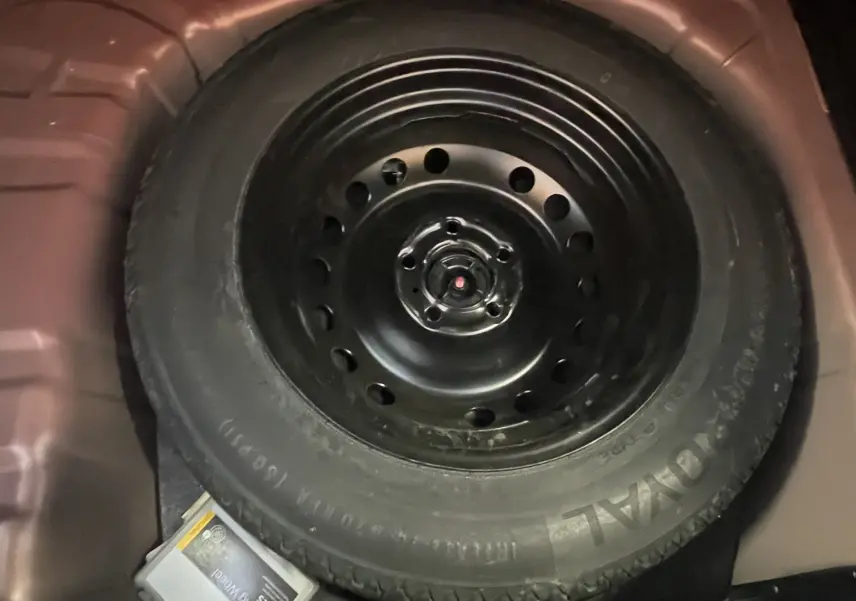 Gros plan sur la roue de secours noire logée dans le coffre rouge du Renault Captur 2019.