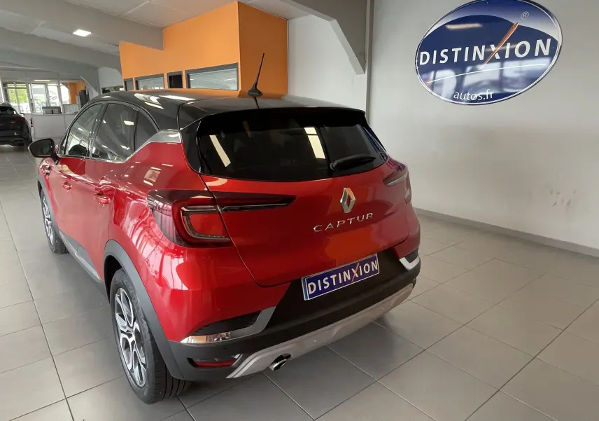 Vue 3/4 arrière du Renault Captur rouge avec toit noir, dans un showroom lumineux avec logo Distinxion.